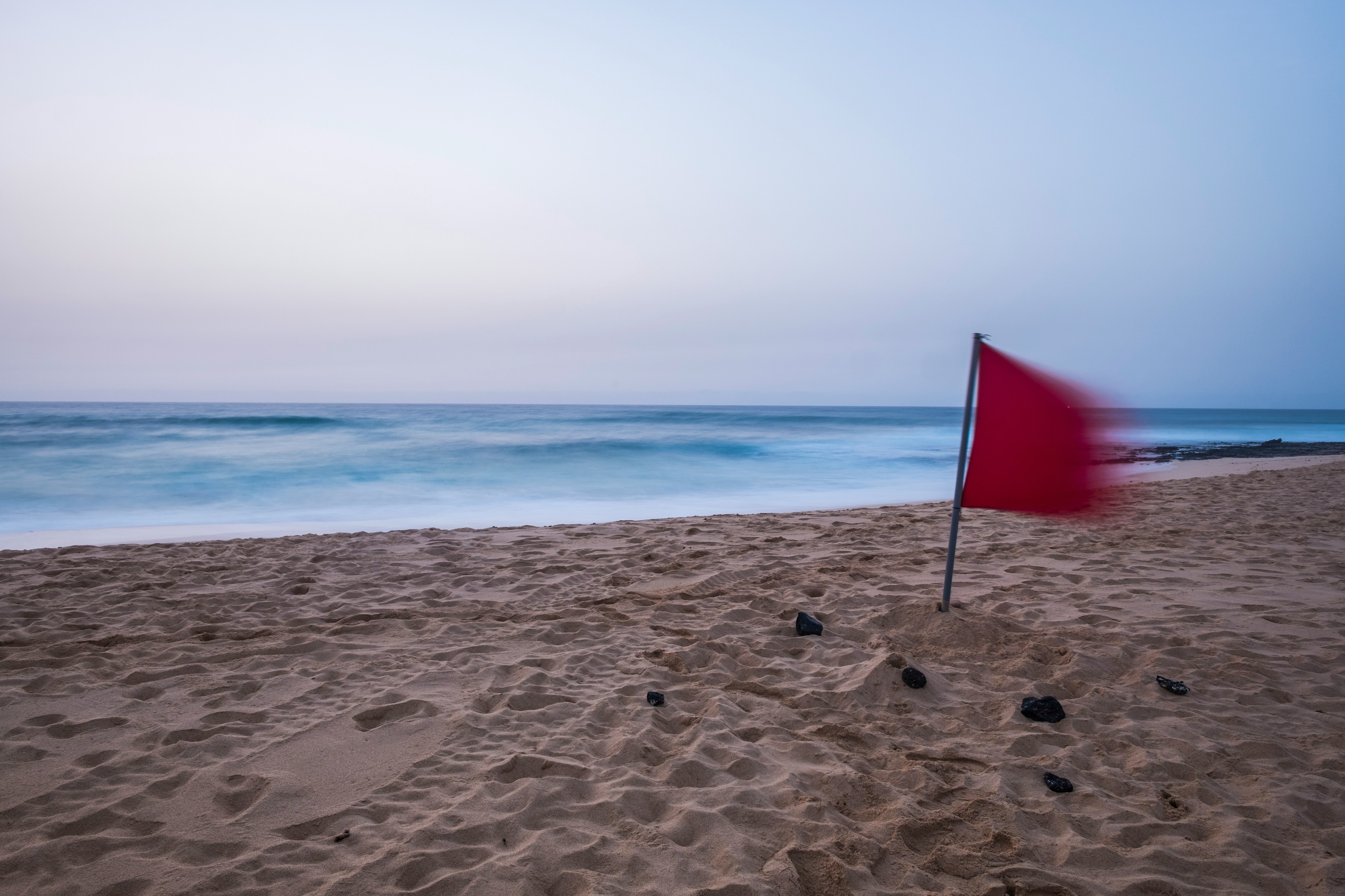 red warning flags beach sunset